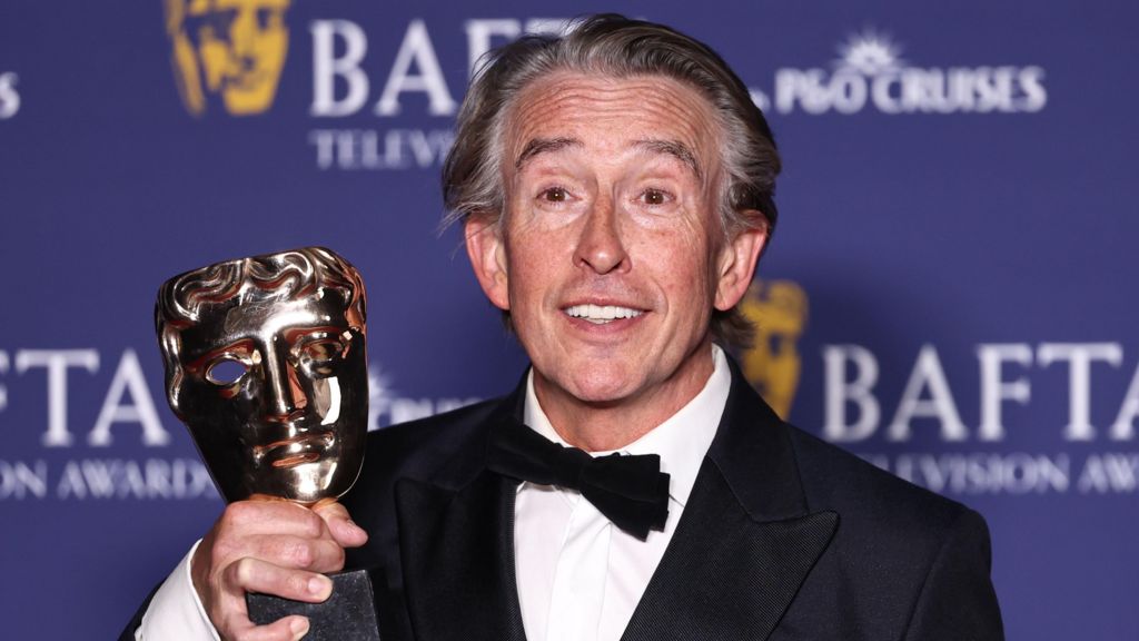 Steve Coogan holding his Bafta trophy