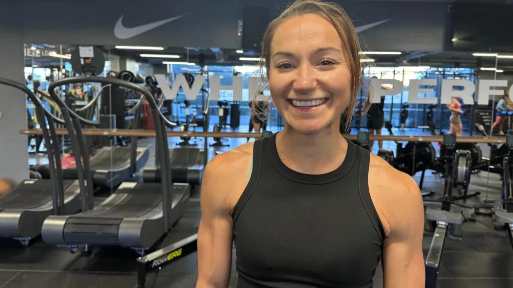 Picture of a woman smiling in front of gym equipment