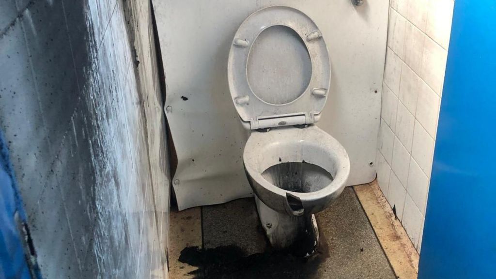 A toilet in Teignmouth left damaged by fire with burnt bowl and seat and smoke damage to the walls and floor