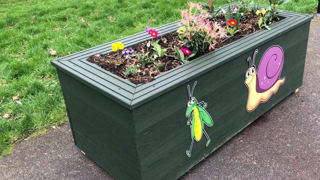 One of the upcycled bathtubs, but cladded with green-painted wood and with flowers planted inside