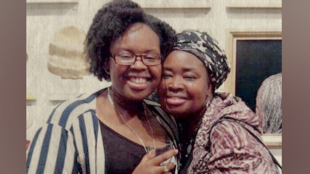 Two women with arms around each other smile for the camera.