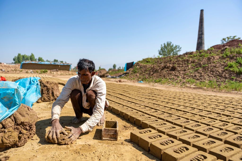 BUDGAM, INDIA - 2024/05/15: A non-local labourer uses a mould to make bricks at a brick kiln in Budgam. The substantial emission of toxic elements from brick kilns poses grave threats to public health and the environment. These kilns release harmful fumes that can adversely affect the eyes, lungs, and throat of individuals exposed to them. In Jammu and Kashmir, traditional brick kilns' pollution concerns are being addressed with a shift to zig zag technology. Zig zag technology introduces a zig zag pattern in the kiln's firing system. This design allows for a more controlled airflow, optimizing the combustion process that helps in achieving better heat distribution, resulting in increased energy efficiency and reduced emissions. (Photo by Idrees Abbas/SOPA Images/LightRocket via Getty Images)