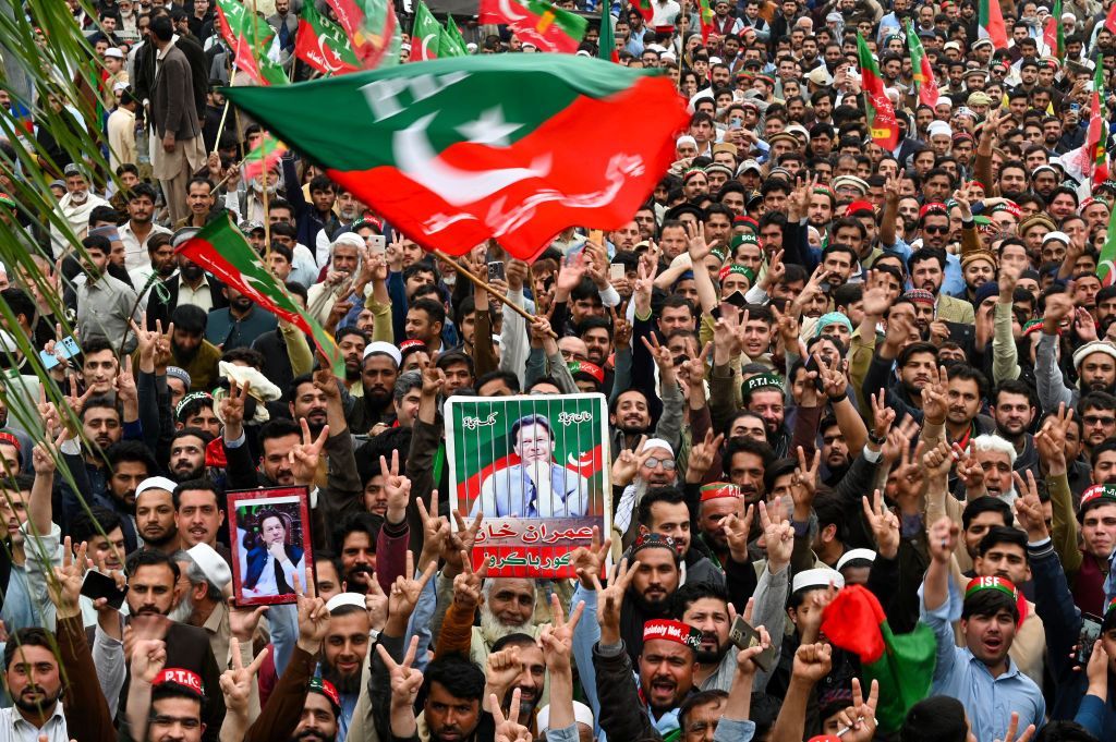 A large crowd waving flags and placards in support of Imran Khan