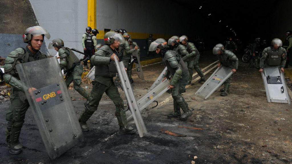 Members of the Bolivarian National Guard of Venezuela use their shields to clean an avenue after a protest from supporters of Venezuelan opposition following the announcement by the National Electoral Council that Venezuela's President Nicolas Maduro won the presidential election, in Caracas