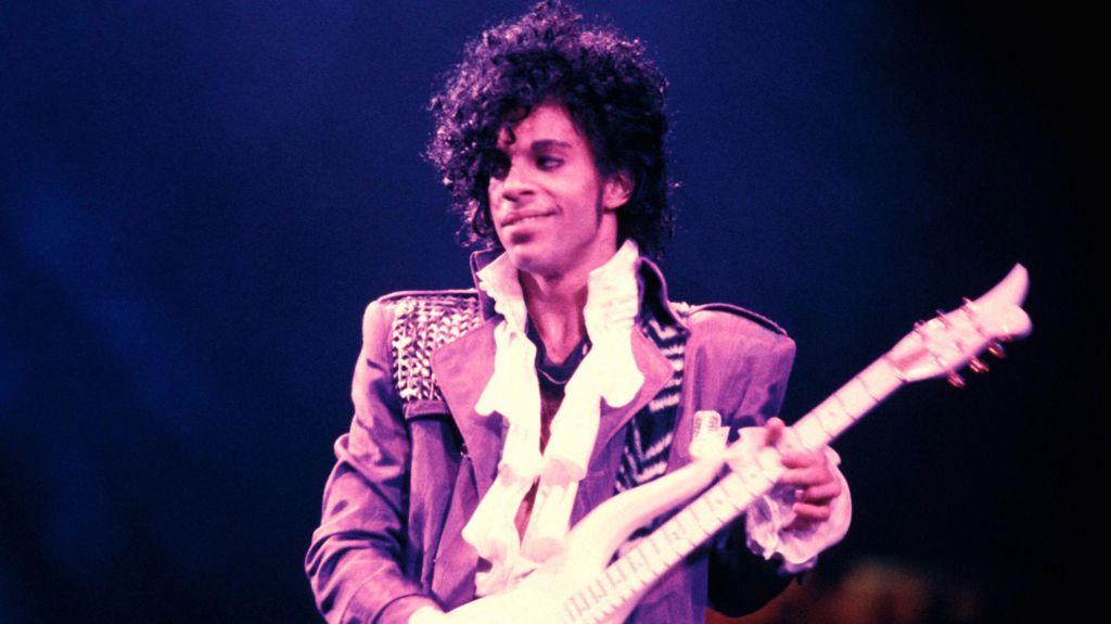 Prince playing the guitar on stage in 1984