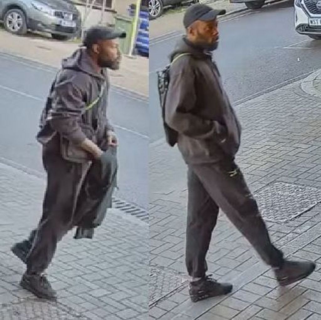 CCTV-style side-by-side images of a man police want to talk to. He is walking along a paved street, wearing a dark baseball cap, dark hooded jacket, tracksuit bottoms and black trainers, and carrying a backpack; parked cars and a kerb are visible in the background.