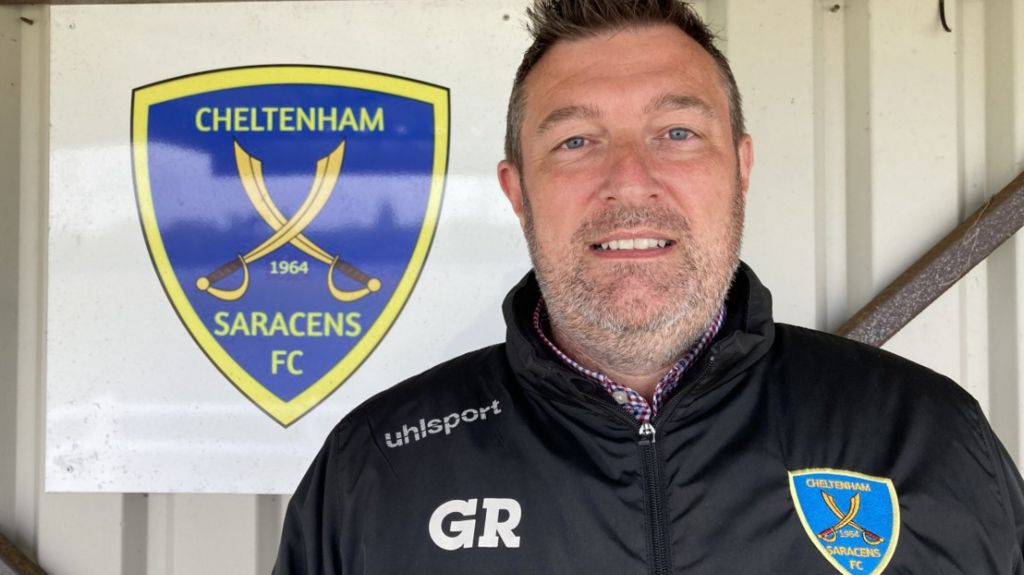 Close-up of Graham Roberts, standing in the present pavilion with a Cheltenham Saracens FC logo behind him