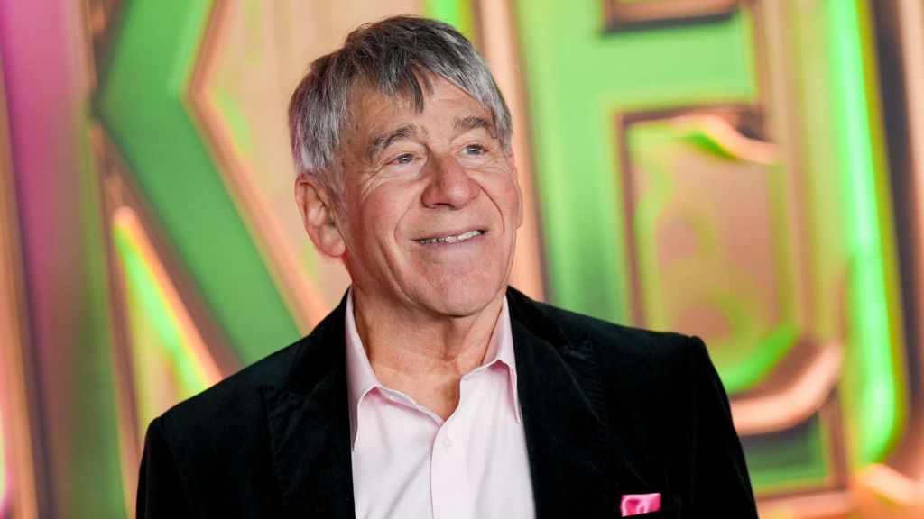 Stephen Schwartz at the "Wicked: For Good" New York Premiere held at Lincoln Center for the Performing Arts. He wears an open-neck pink shirt and black blazer.