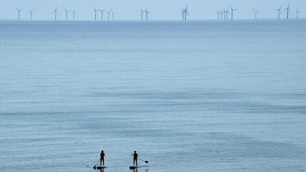 Two surfers look at the rampion farm in the sea