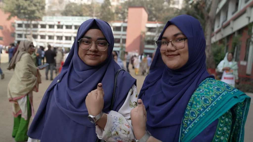 A couple of young women in Bangladesh smile and give the thumbs up sign