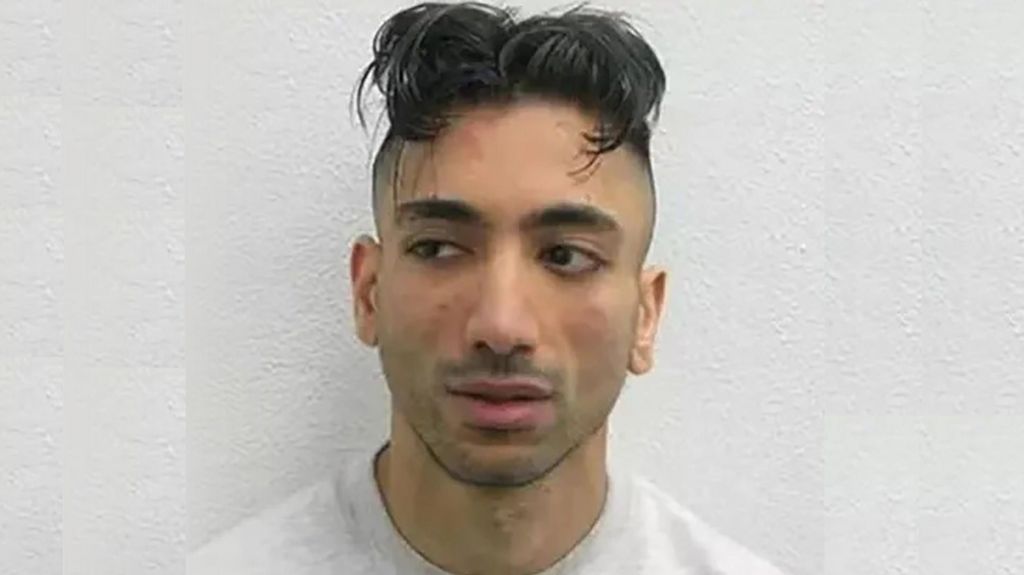 A mugshot of Jacky Jhaj, wearing a white jumper.