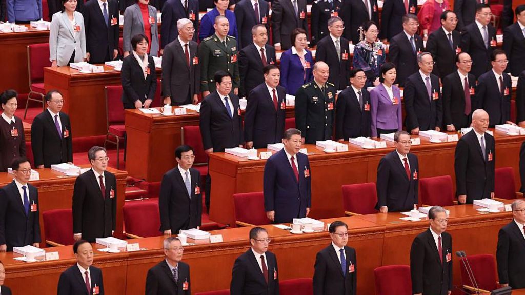 Chinese officials, including President Xi Jinping at the centre of the image, stand by their seats at the opening session of the National People's Congress held at the Great Hall of the People in Beijing 