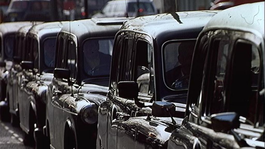 A row of black taxis wait for fares