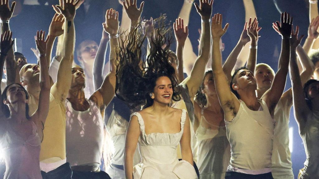 Rosalia flicks her hair up while performing during the Brit Awards backed by dancers with their hands in the air