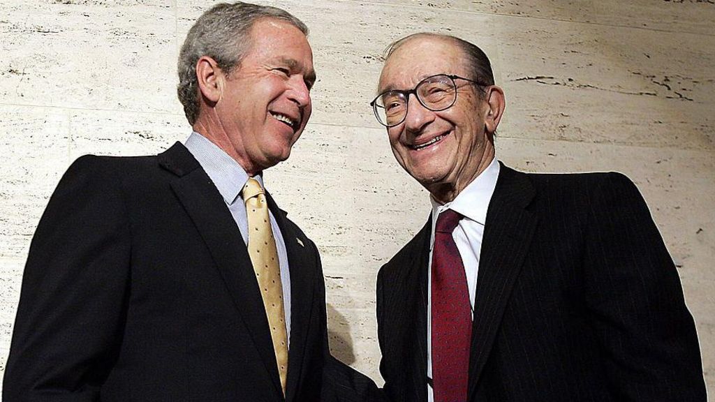 George W. Bush and Alan Greenspan are photographed together. They are smiling and posing for the cameras