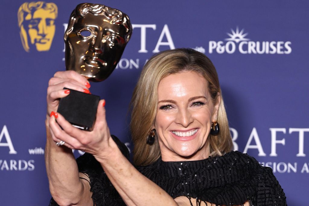 Gabby Logan smiling and holding a Bafta aloft with both hands