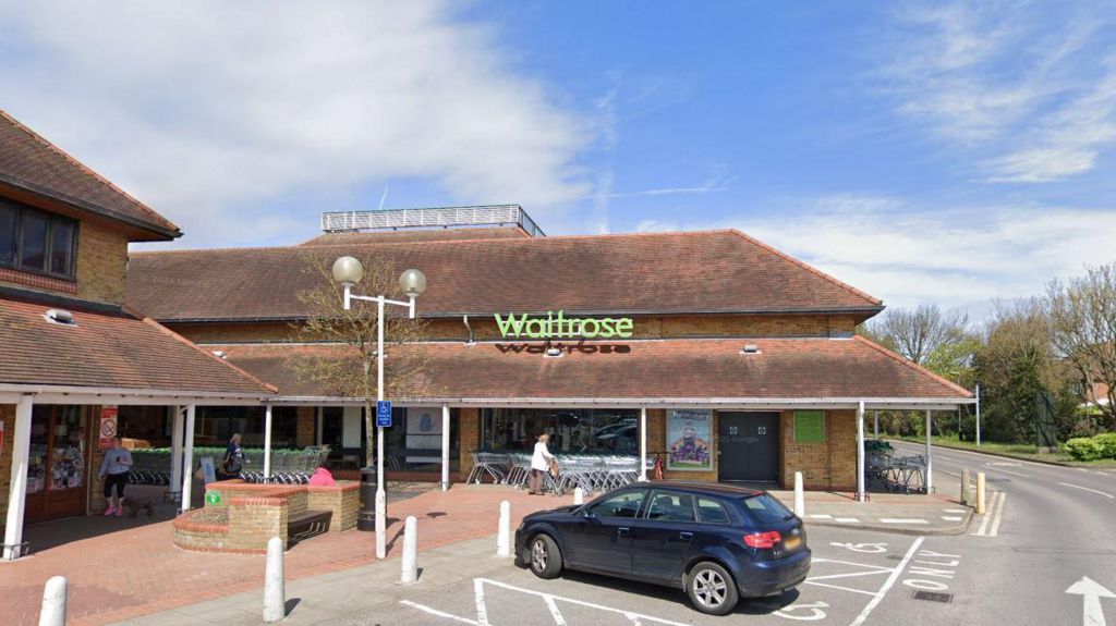 A car is parked outside a Waitrose supermarket.