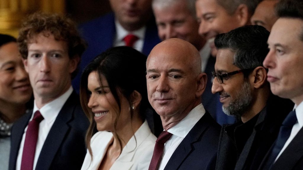 From left to right: Meta CEO Mark Zuckerberg wearing a navy suit, red neck tie and white dress shirt; Lauren Sanchez, wife of Amazon founder and former CEO Jeff Bezos, wearing a white blazer; Jeff Bezos, in a navy suit, red neck tie and white dress shirt; Google CEO Sundar Pichai, in an all black coat, shirt and tie.