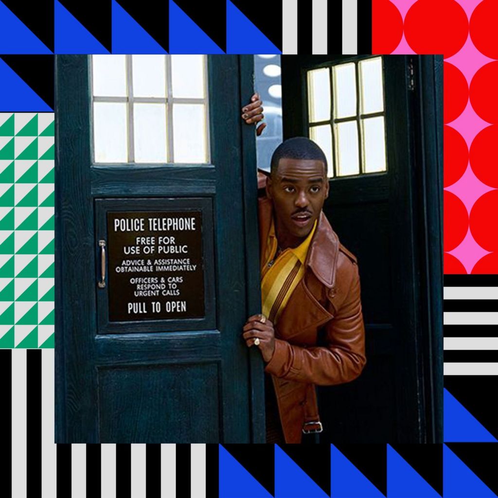 Ncuti Gatwa playing the role of The Doctor, peeking out of a blue telephone box. He is wearing a brown leather jacket and yellow shirt