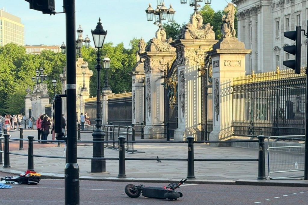 An e-scooter horizontally on a road outside Buckingham Palace gates. 