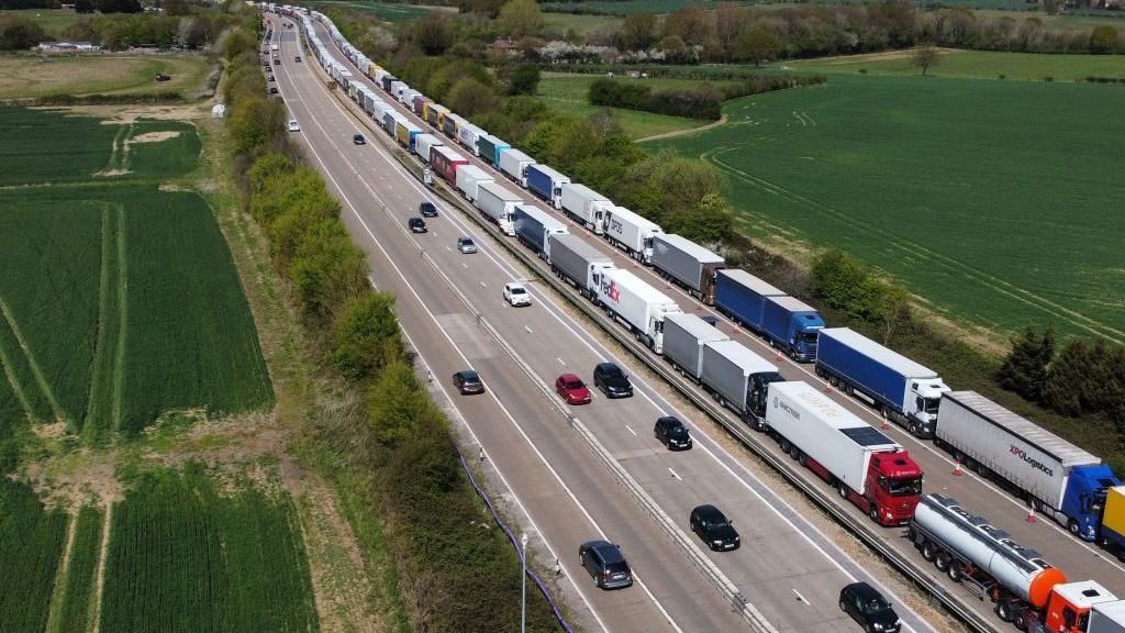 Lorries queue on one side of the M20 motorway while cars pass on the other side