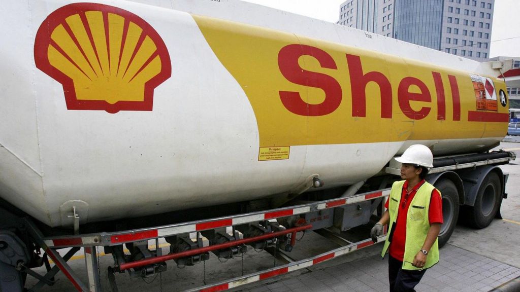 A shell branded petrol tanker with a woman wearing a white safety hat and hi-viz vest standing next to it