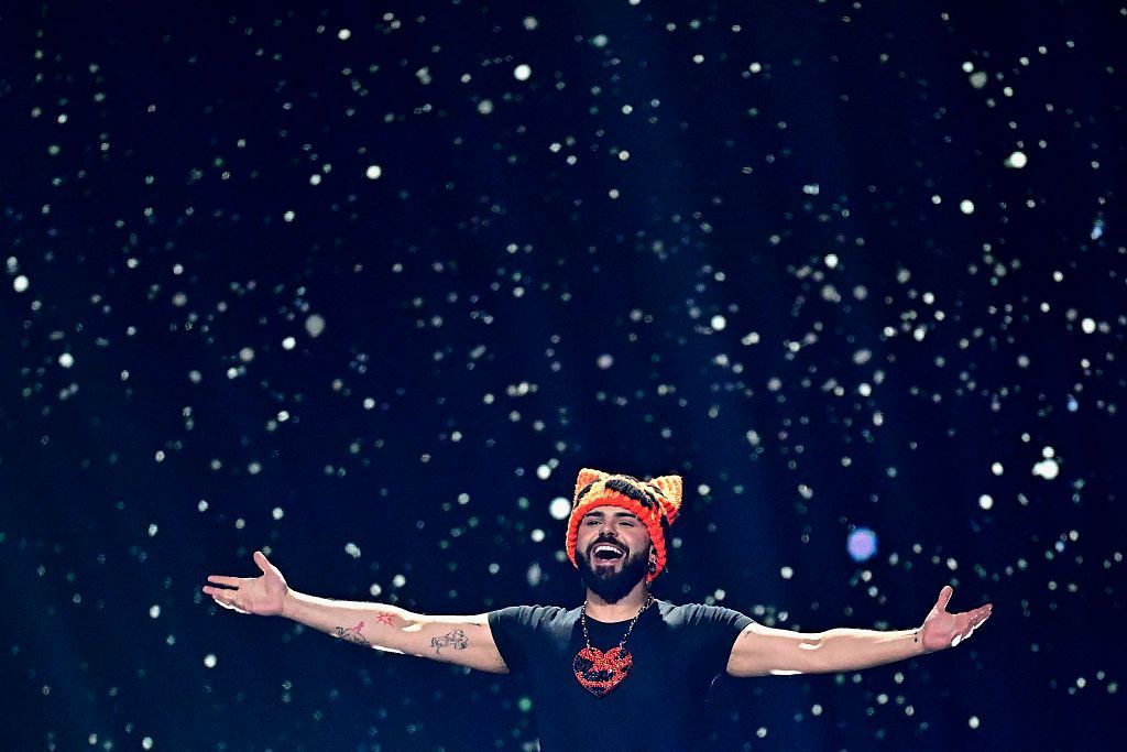 Akylas in a black T shirt and an orange hat with ears with his arms outstretched