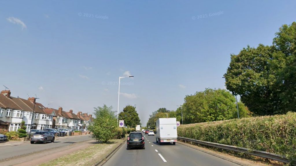 A google street view showing Great Cambridge Road. It is a dual carraigeway with some hedges on one side and a row of houses on the other