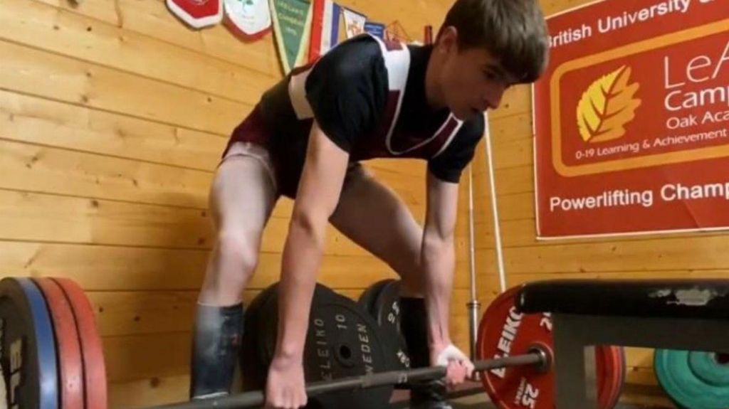 Harvey Chester preparing to lift a barbell with red and blue plates on the ends