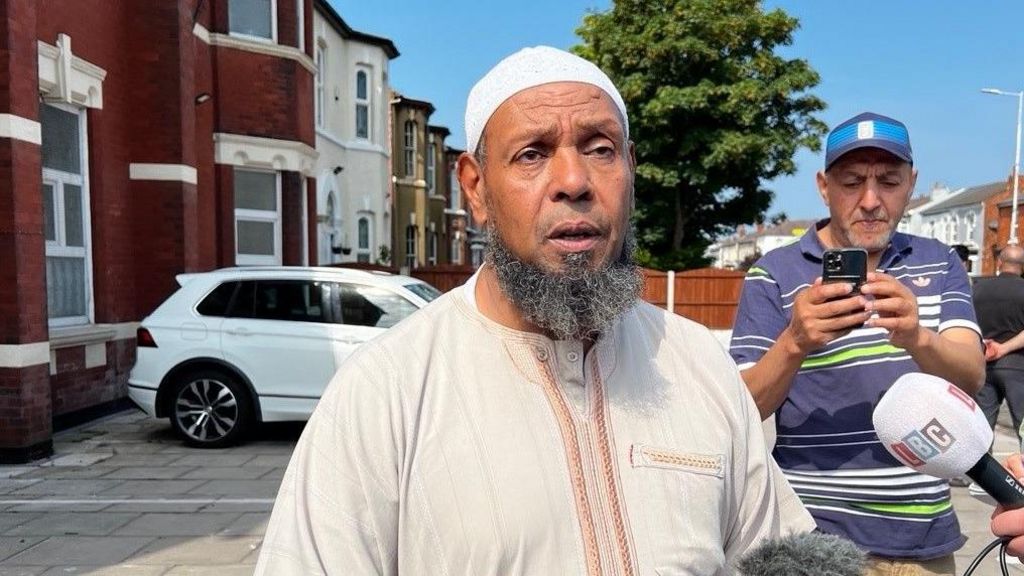 Chairman of the Southport Mosque Ibrahim Hussein is interviewed by reporters in the town