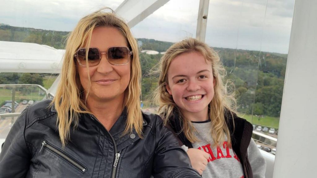 Maisie Summers-Newton and her mother Laura pose in a cable car. Laura is a blonde haired woman and wears sunglasses and a black leather jacket. Maisie is also blonde, and wear a grey sweatshirt and black gilet. 