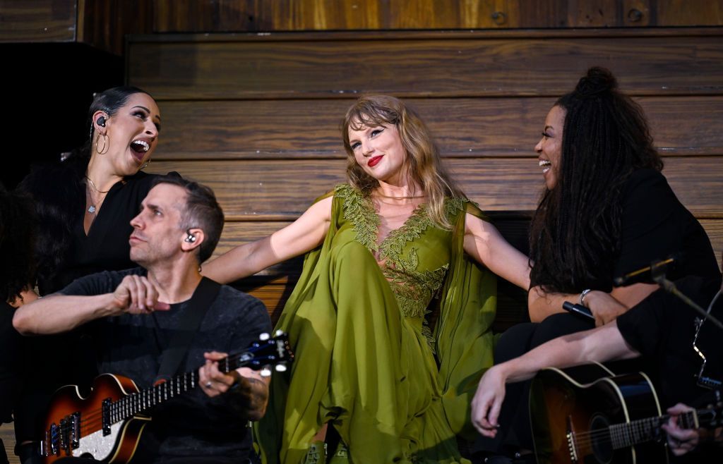 Taylor Swift holds hands with her backing singers during a performance on her Eras tour