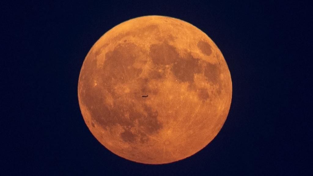 A plane flies in front of the Moon in Toronto