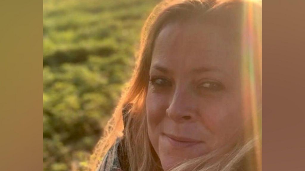 Annabel Rook, a woman with blonde hair, turns to look at the camera in low sun