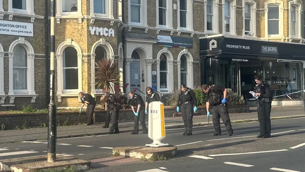 Police officers sweeping a street for evidence