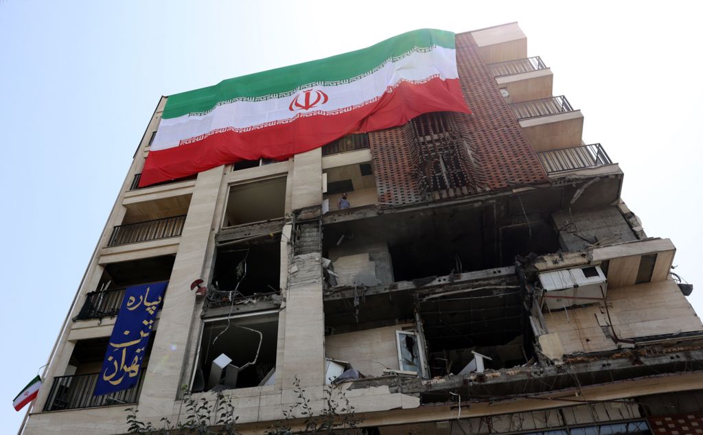 A large-scale national flag hangs from a damaged building that was hit by a recent Israeli airstrike, in Tehran, Iran.