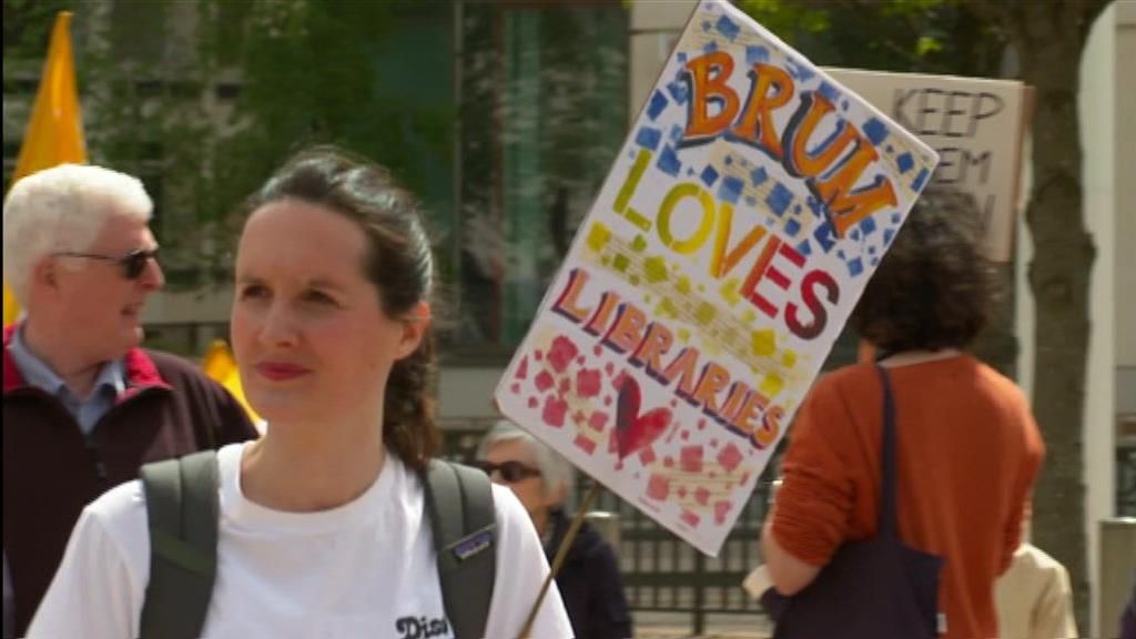 A protester with a 'Brum loves libraries' sign