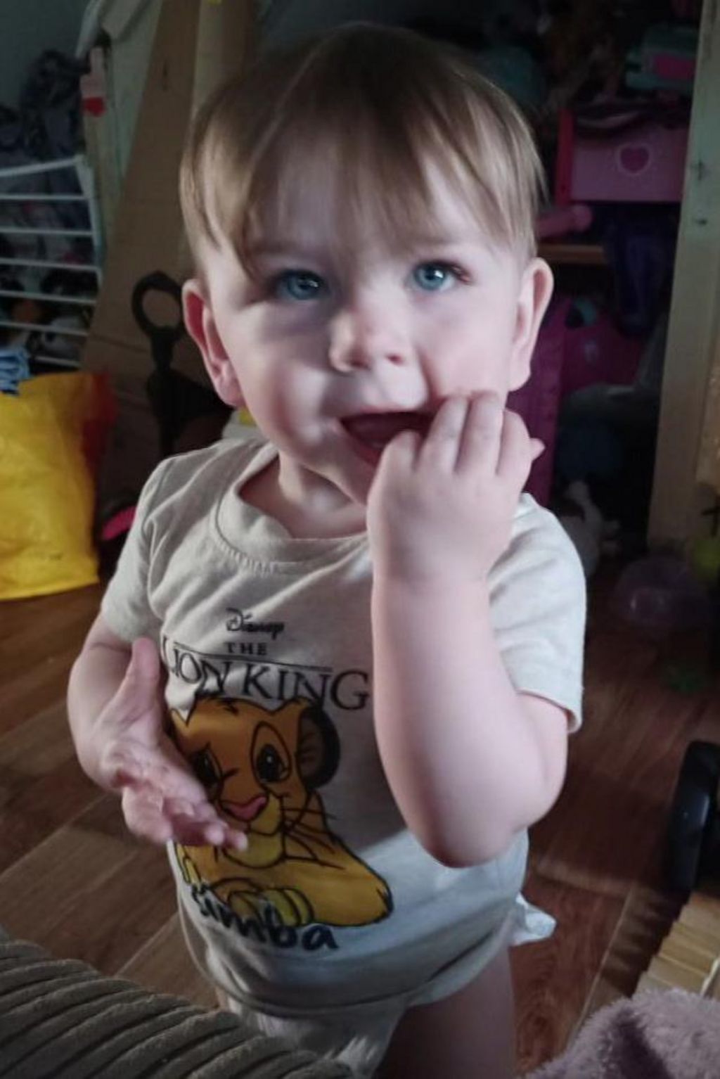 Kol Page as a young toddler, wearing a nappy and a T-shirt with 'The Lion King' on it and a character from the film. He is looking up at the camera, with his fingers in his mouth.