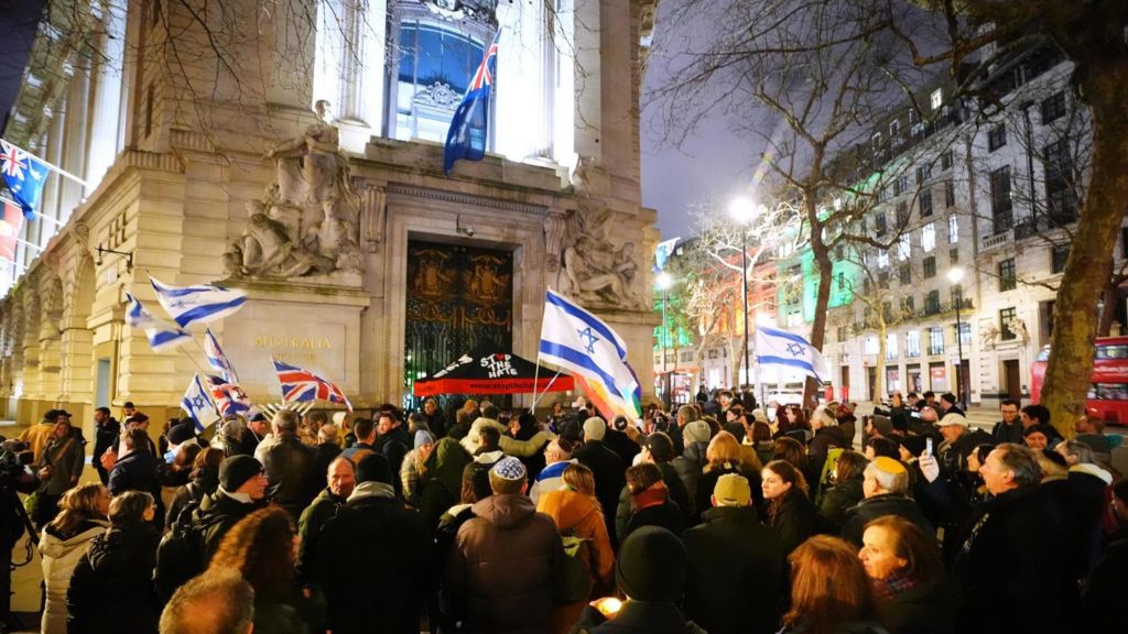 Crowds outside Australia House in London. A small number of people can be seen waving Israel and UK flags