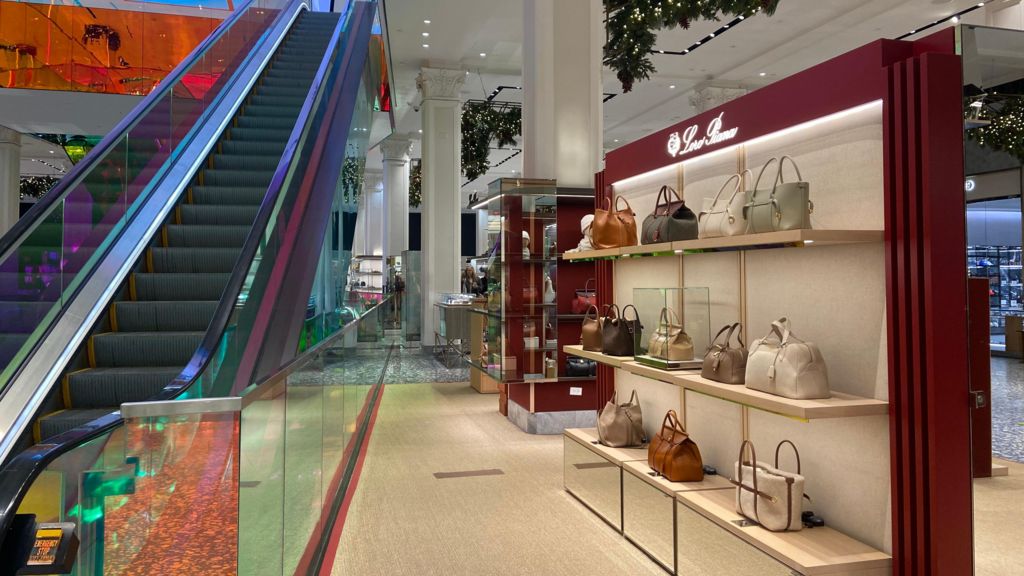 Bags are showcased next to as escalator in a department store.