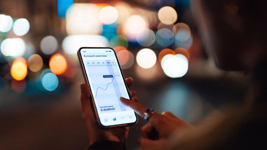 Over the shoulder shot of somebody looking at financial performance on a smartphone