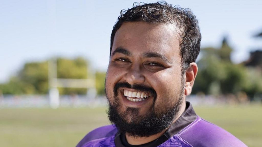 Ras Ahmed in a purple top smiling at the camera