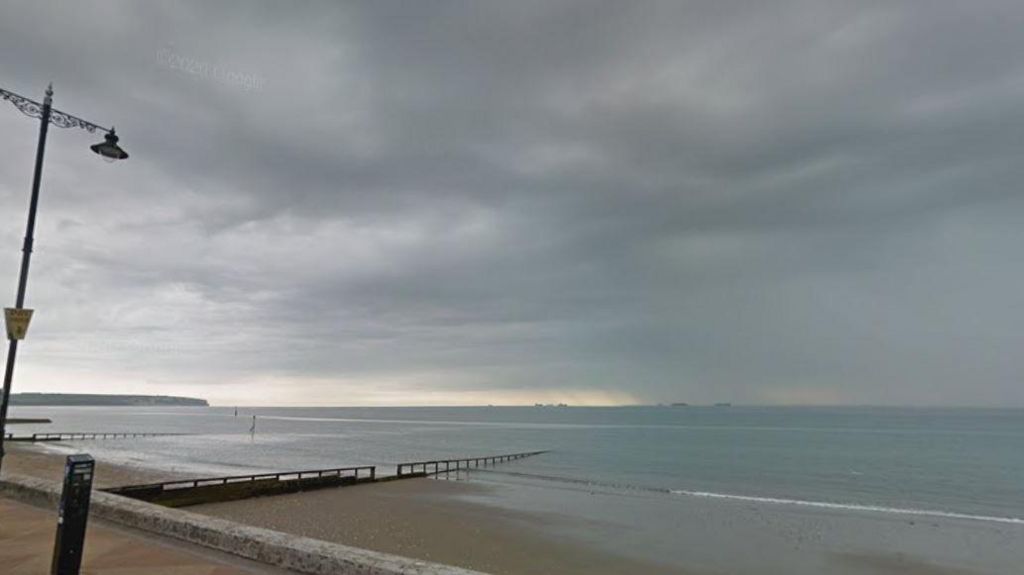 A section of the beach in Shanklin. There is a lamppost to the left of the frame and a small part of the pavement can be seen, with a small section of pebbled beach leading into the sea.