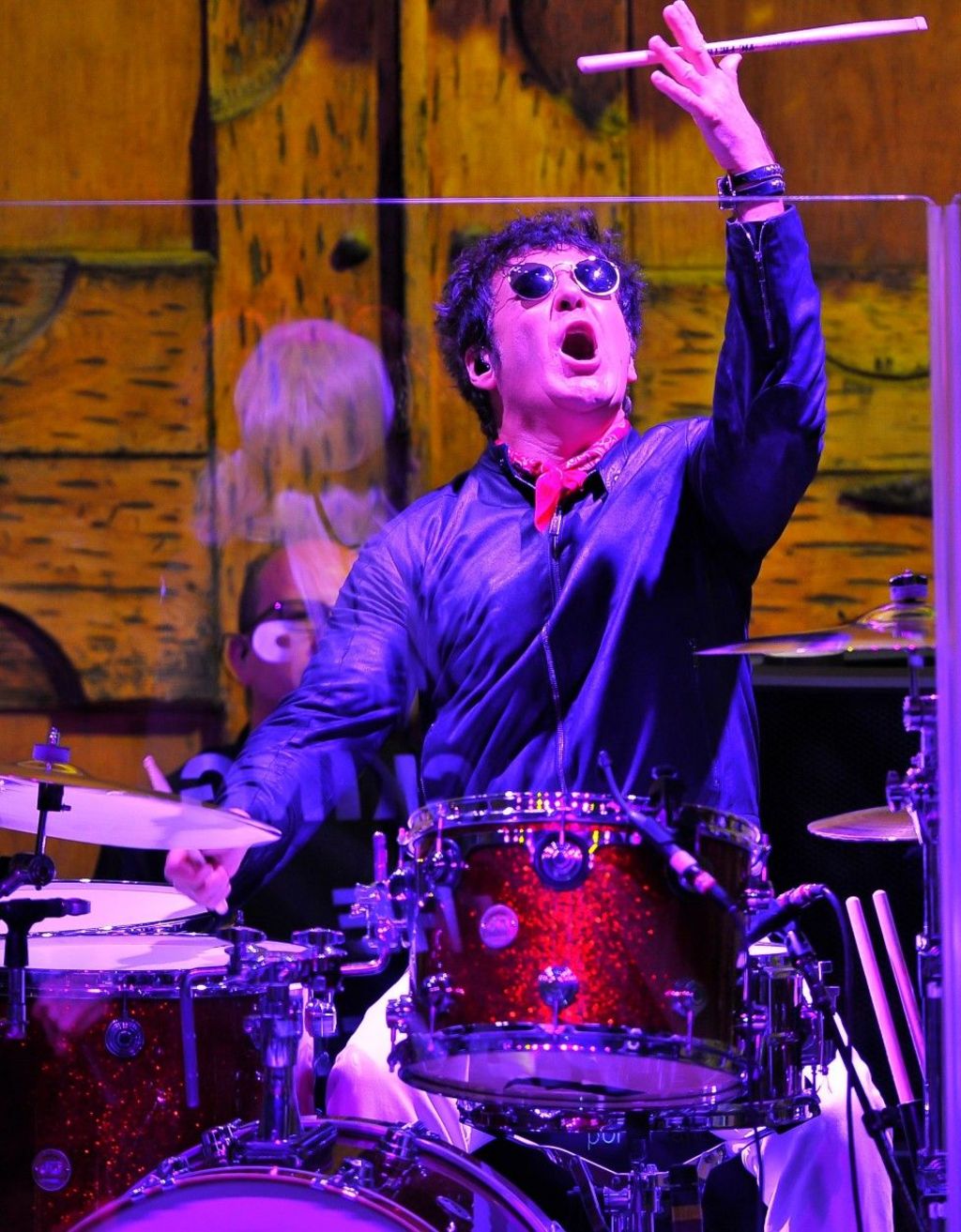 Clem Burke wearing sunglasses while spinning his drum sticks in the air