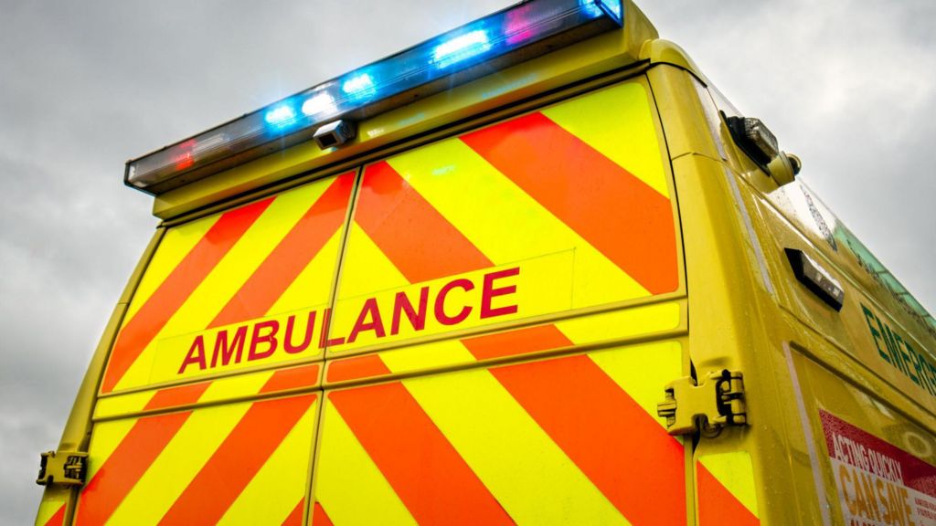 The rear view of an ambulance - a yellow vehicle with orange stripes