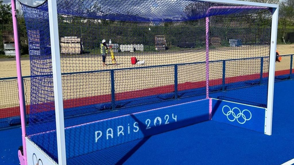 A pink, blue and white coloured hockey goal with the logo Paris 2024 inscribed on bottom board