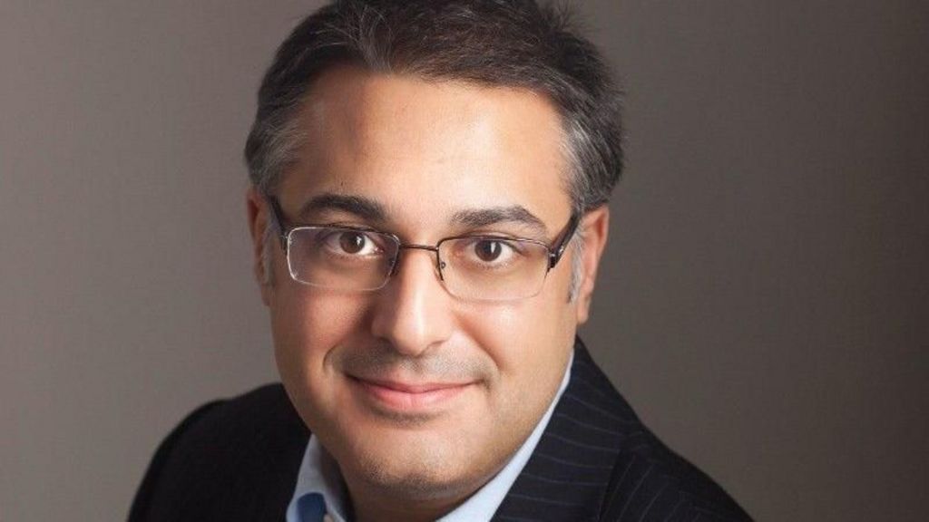 An image of Yaser Jabbar. He has dark hair, is wearing clear glasses and is dressed in a suit