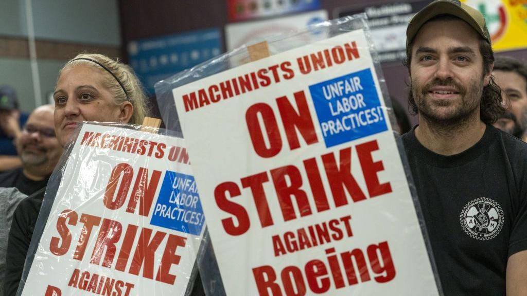 Union members hold picket signs during a news conference.