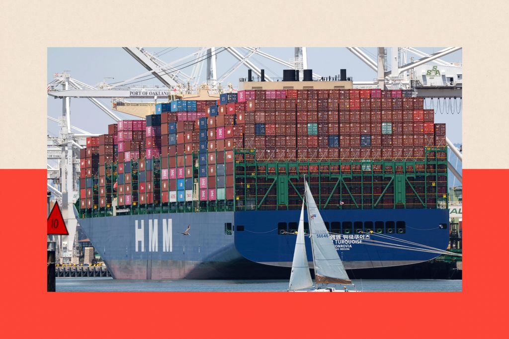 A sailboat sails past a container ship at the Port of Oakland in Oakland, California