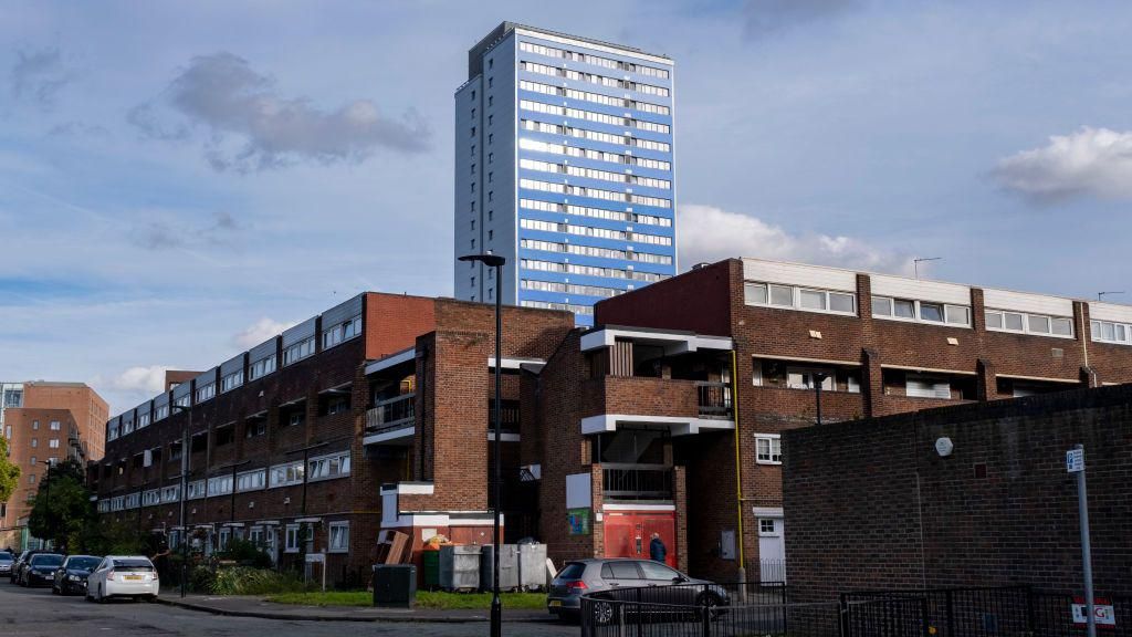 Image showing old brick blocks of flats with a glass and metal high-rise block in the distance in Canning Town